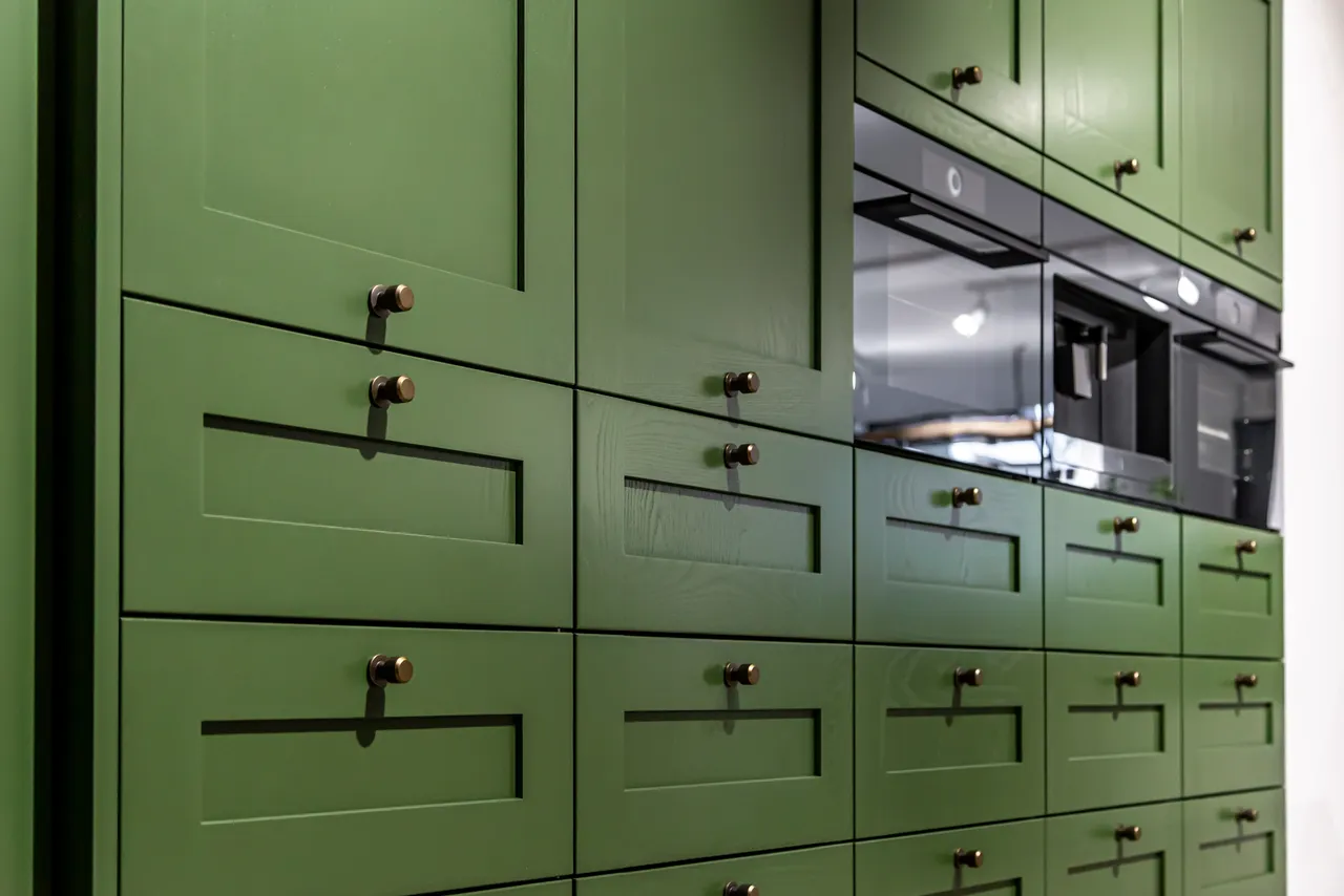 Green kitchen cabinets with bronze knobs