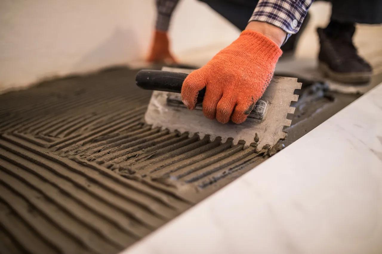 man installing tiles in bathroom