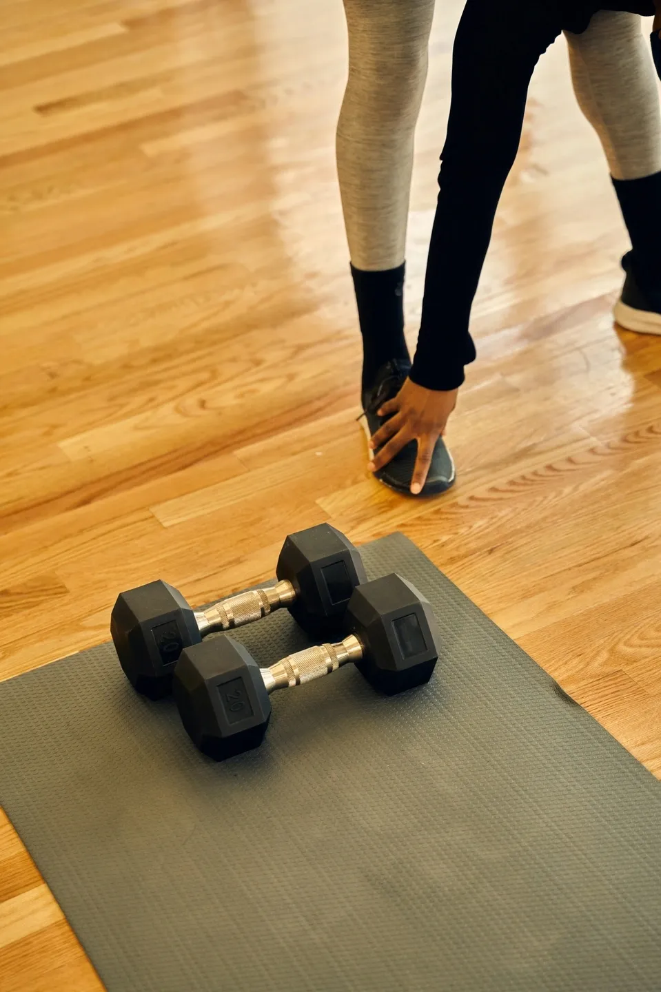 Yoga mat with weights, person stretching in their home gym