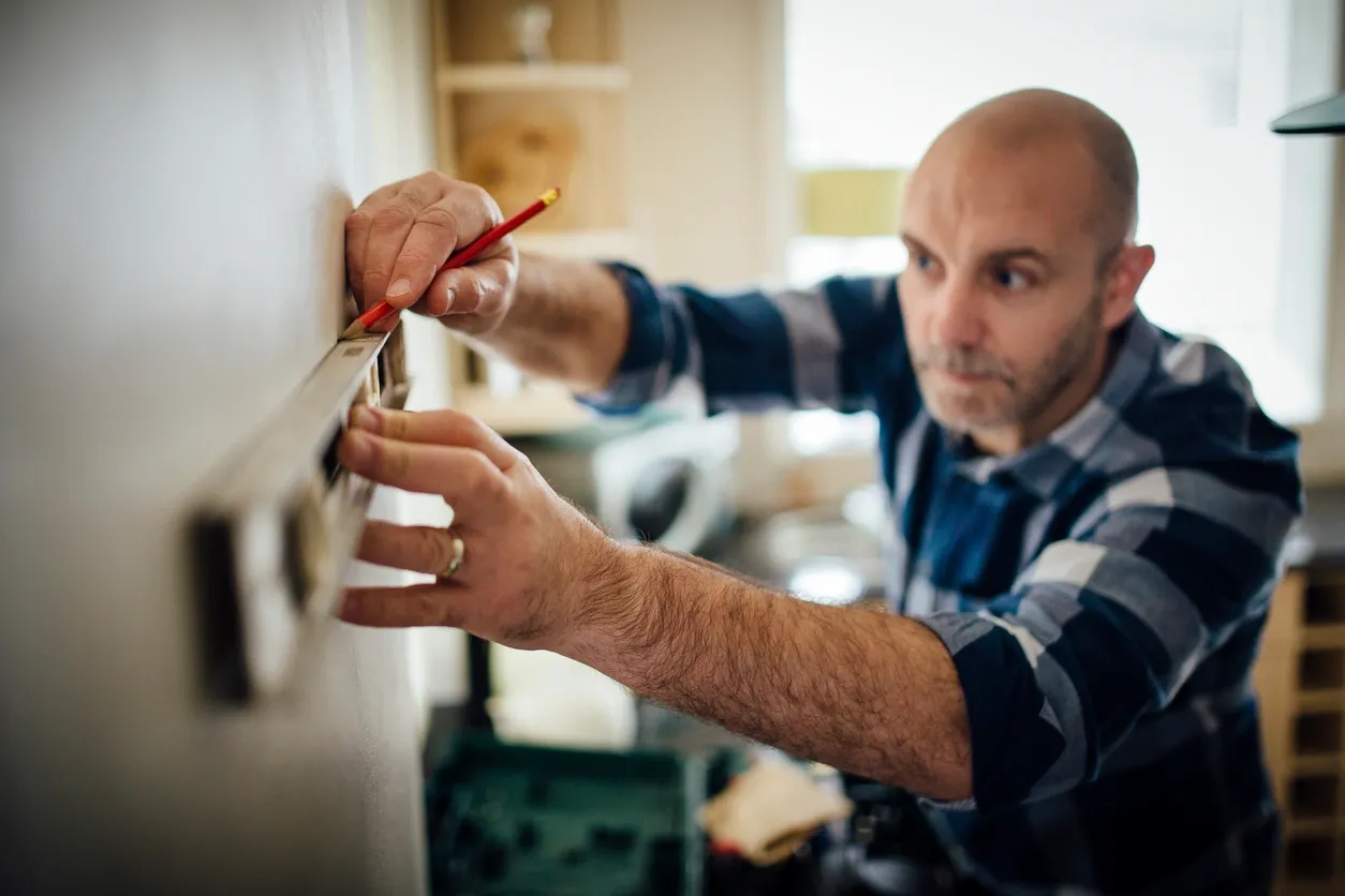 Professional Tradesperson uses a levelling instrument on a wall