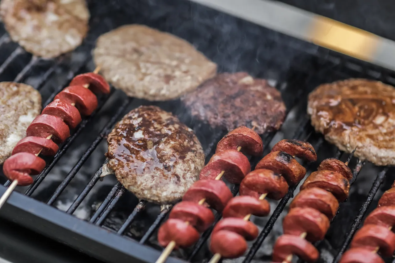 Burgers and sausages being cooked on the barbeque.