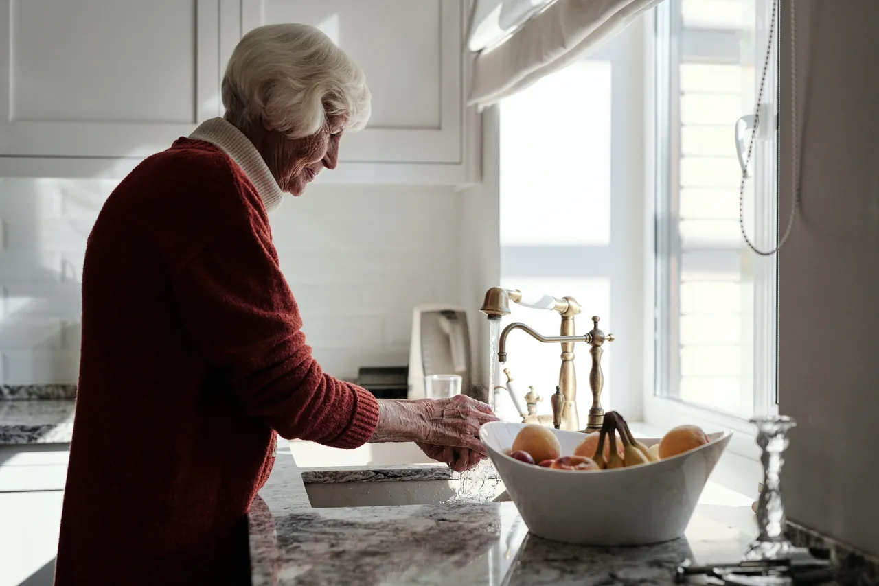 An elderly woman washing the dishes.