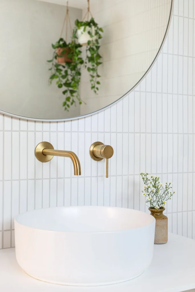 Modern bathroom remodel in Vancouver by Quay Construction featuring a white vessel sink, gold wall-mounted faucet, and vertical stack bond tile.