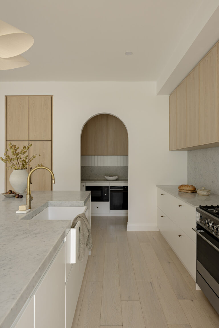 Modern classic Austin Heights kitchen renovation with natural oak cabinets, arched niche, marble countertops, and brass fixtures by QUAY Construction Coquitlam