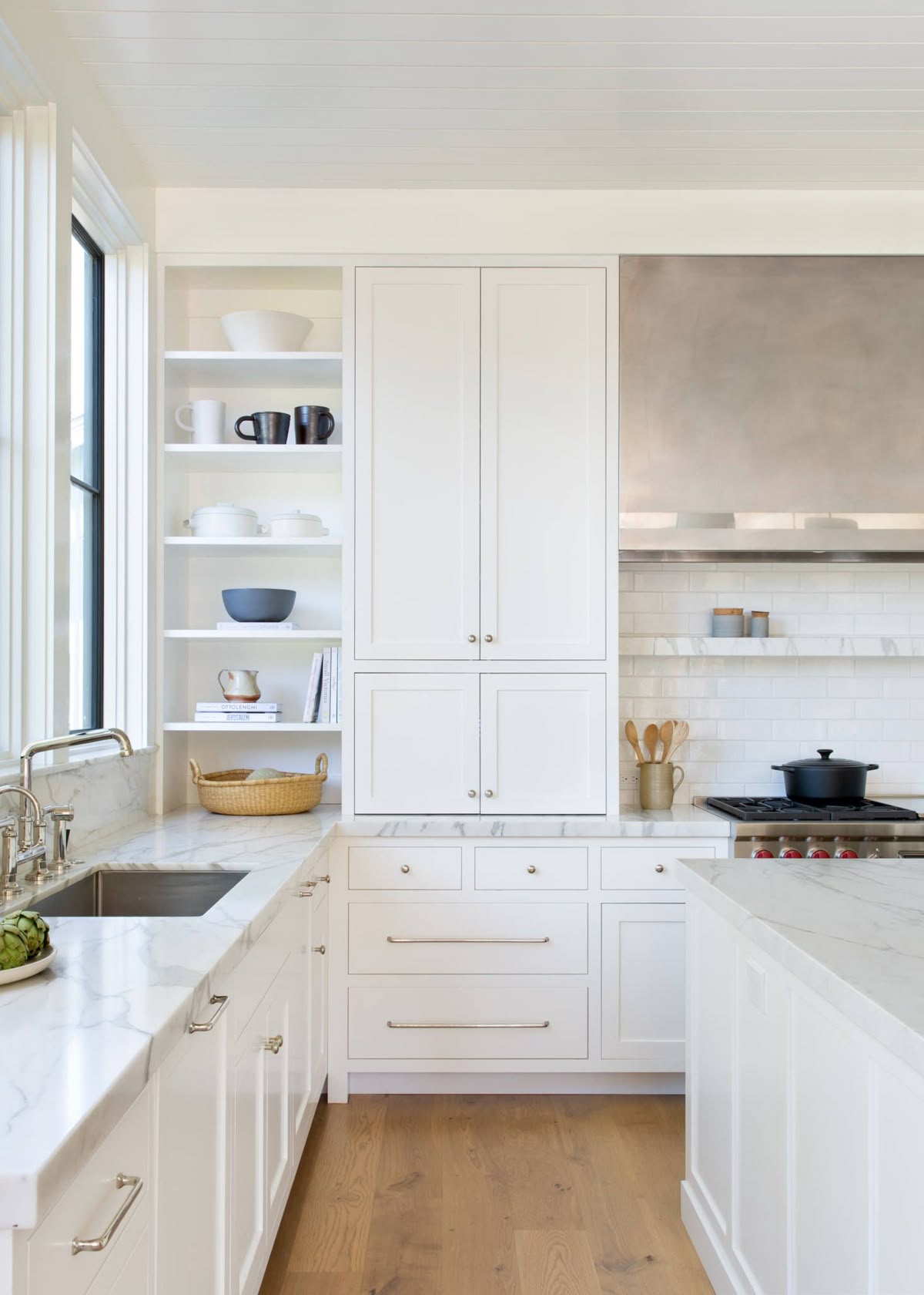 Classic Burke Mountain white kitchen renovation with marble countertops, subway tile backsplash, open shelving, and polished nickel hardware on shaker cabinets