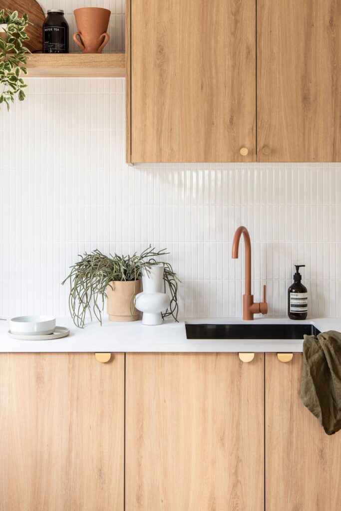 Modern kitchen renovation in Coquitlam featuring flat-panel wood base cabinets, white upper cabinets, and a peninsula with seating, representing a mid-range cost project.