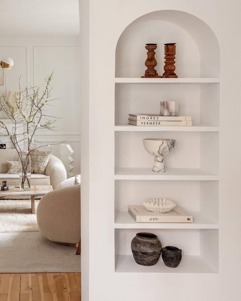 Feature image of a Maillardville home renovation showing a modern arched built-in shelving niche with curated decor, looking through to a neutral, contemporary living room