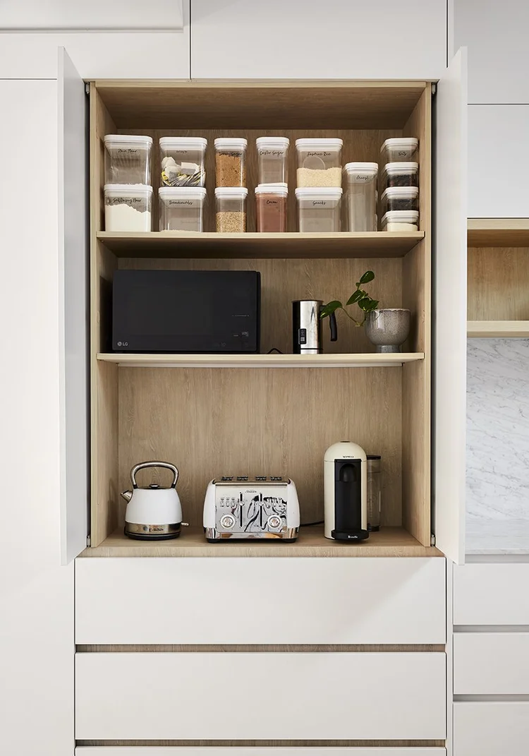 Modern kitchen pantry from a home renovation in Kensington-Cedar Cottage featuring white pocket doors, oak shelving, and organized glass containers with countertop appliances.
