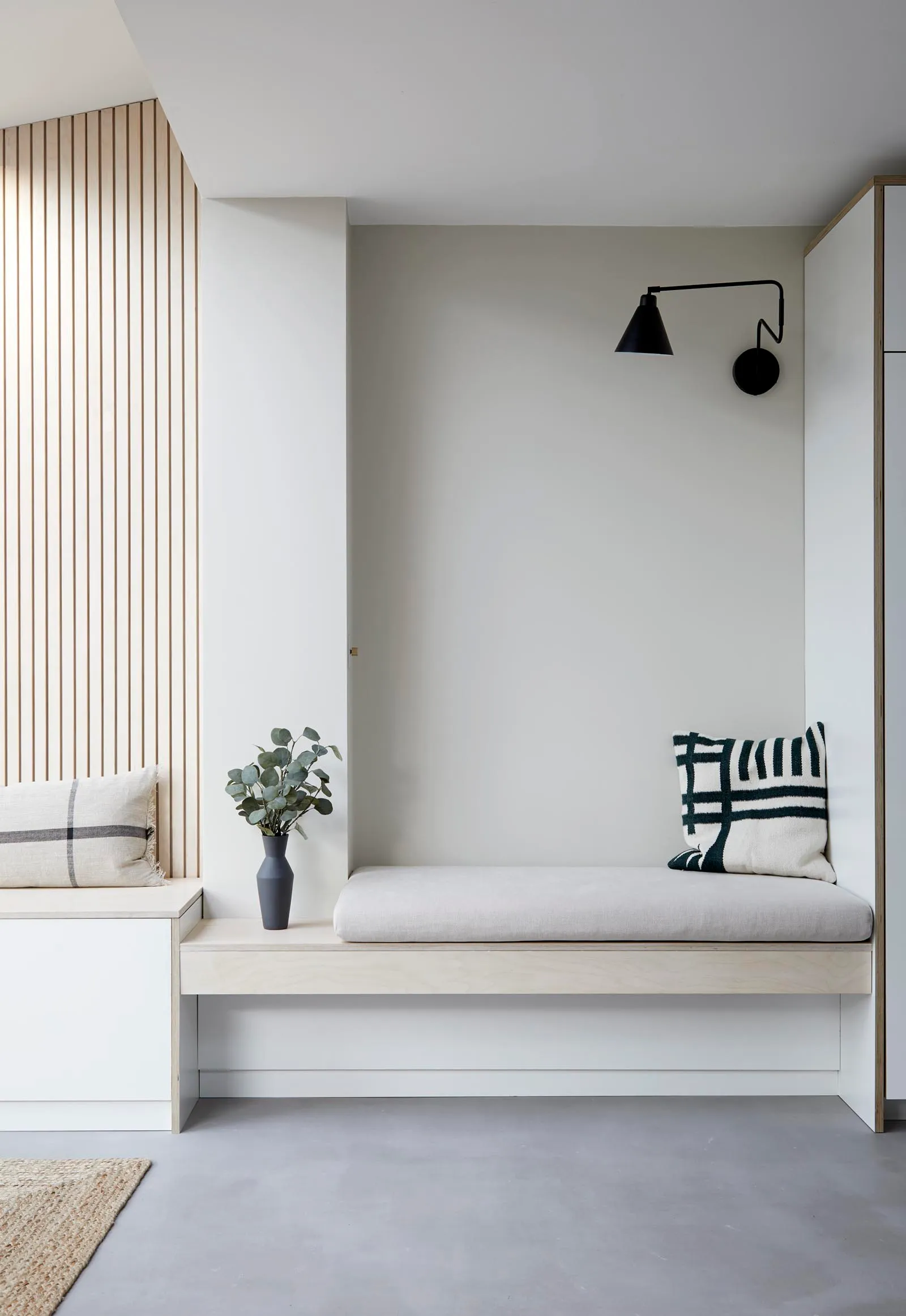 Custom built-in entryway bench with slatted wood wall detailing and minimalist lighting from a home renovation in West Cambie by Quay Construction.