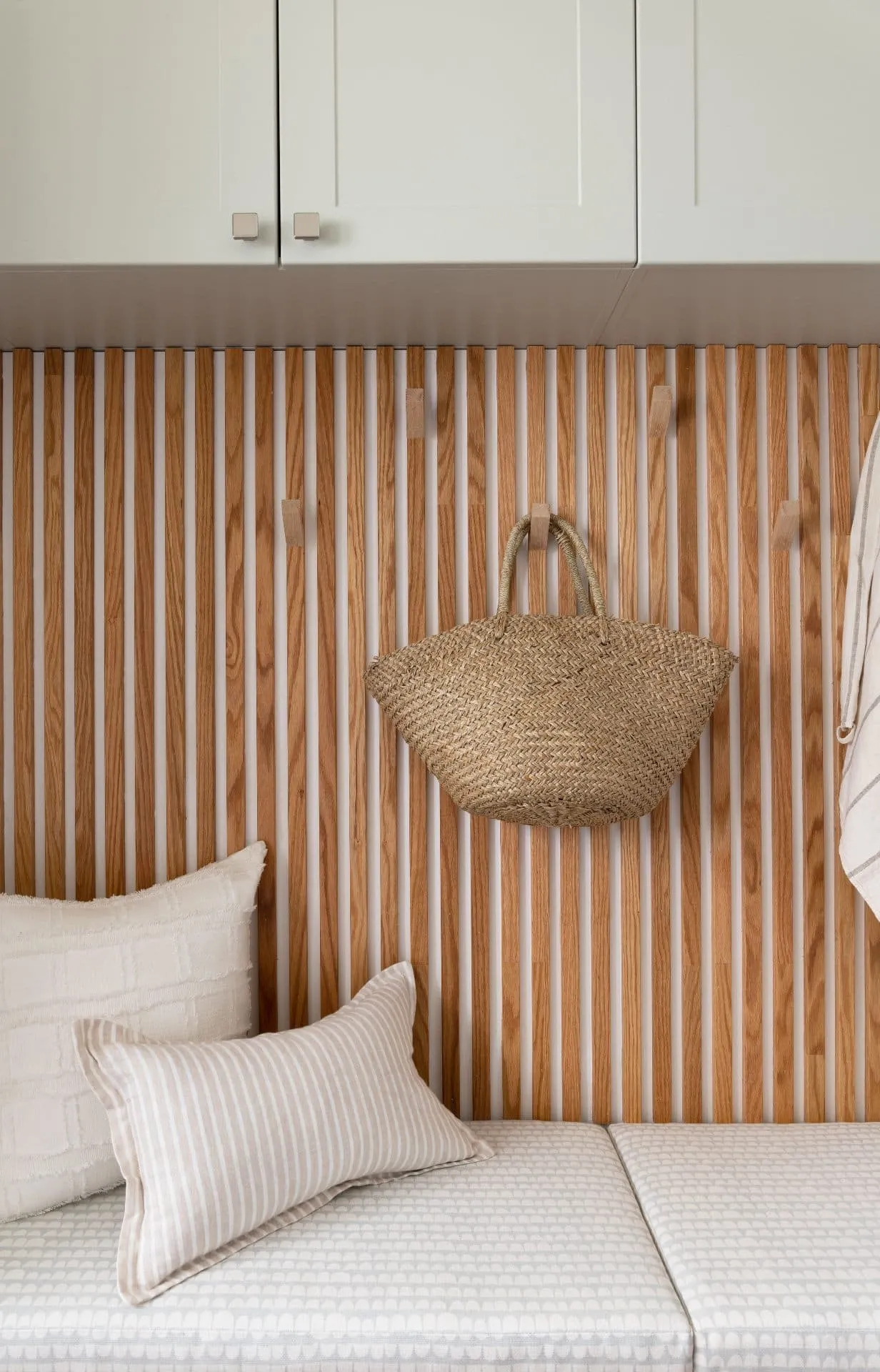 Custom mudroom renovation in City Centre, Richmond, featuring an oak slat wall with integrated hooks and a cushioned bench.