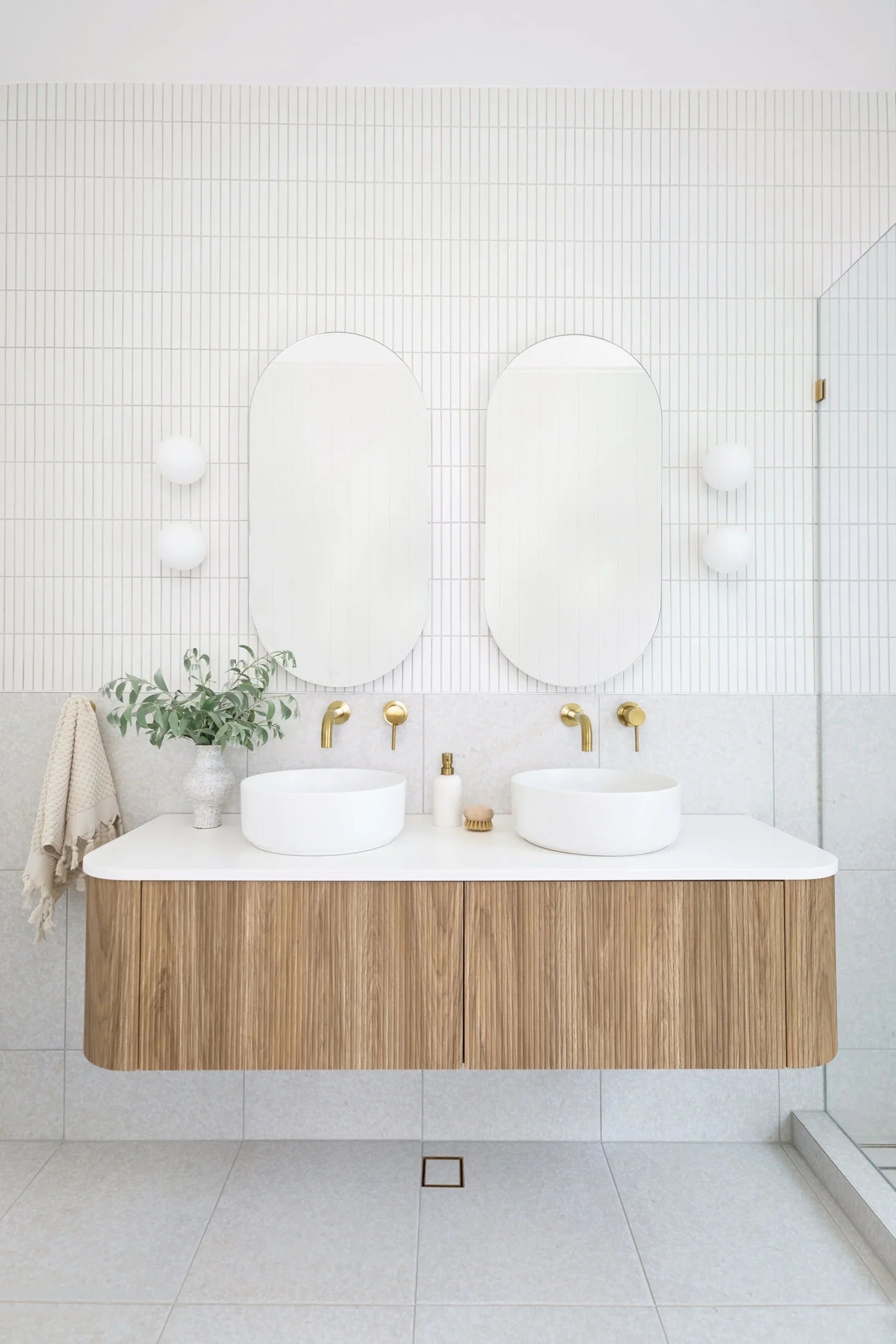 Luxury master bathroom renovation in Deer Lake by Quay Construction featuring a floating wood vanity, vessel sinks, and backlit arched mirrors.