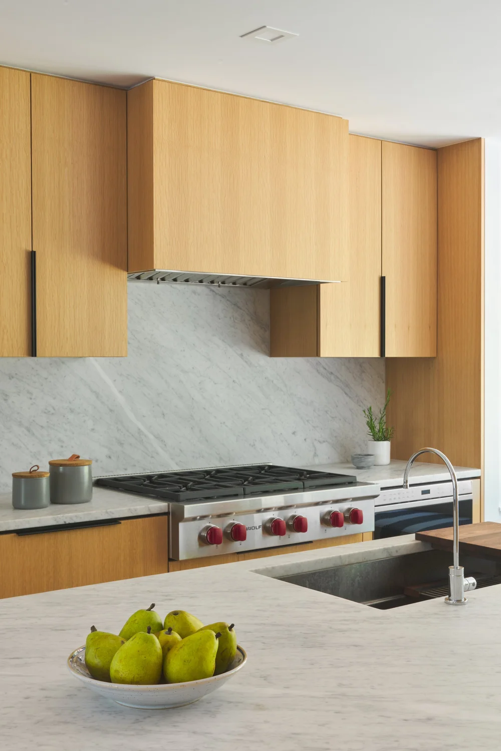 Luxury kitchen renovation in Deer Lake by Quay Construction featuring floor-to-ceiling white oak cabinetry and a marble waterfall island with brass fixtures.