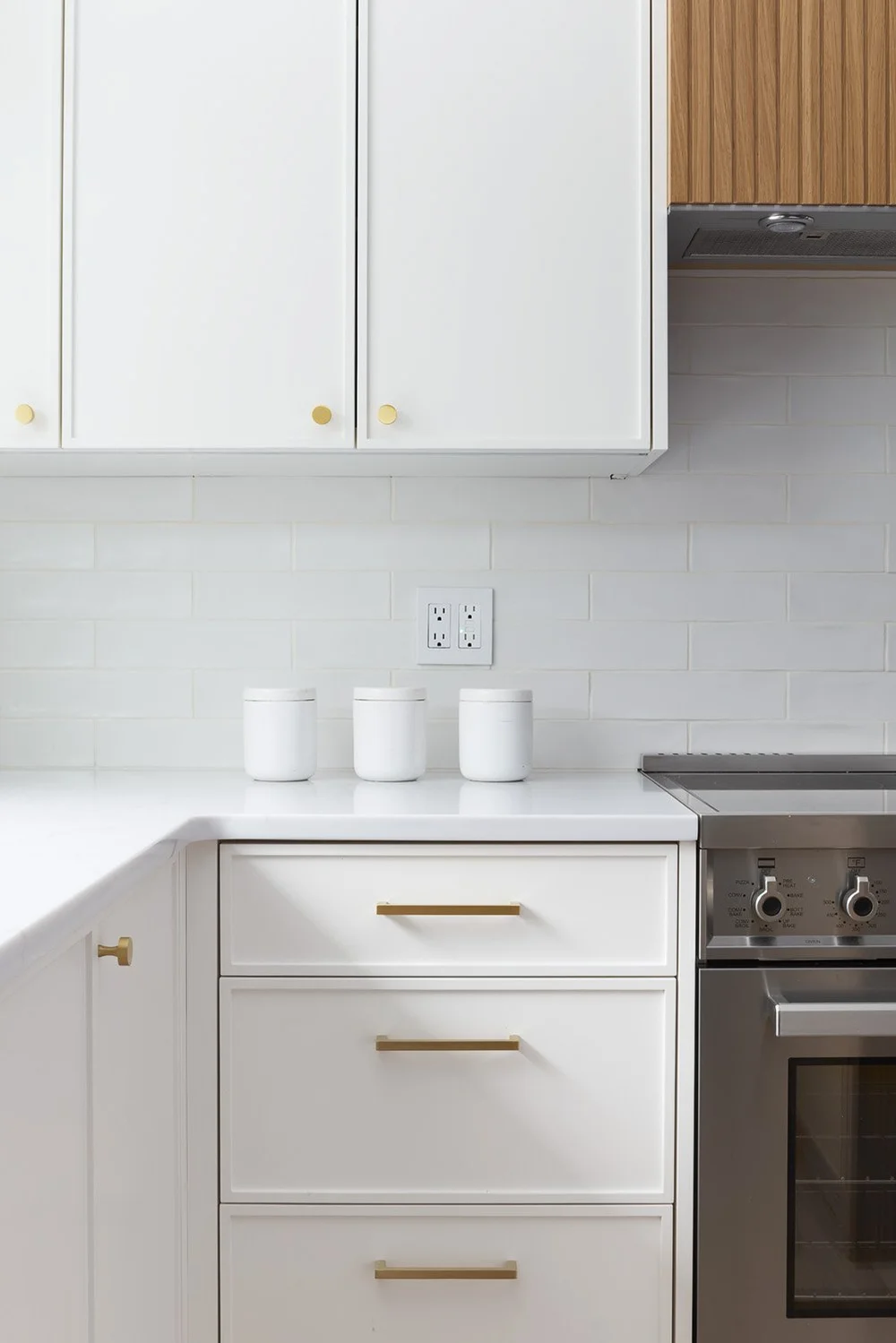 Full view of a Surrey kitchen renovation featuring a large island with wood stools, sage green cabinetry, white Zellige tile backsplash, and a custom arched wood pantry door.