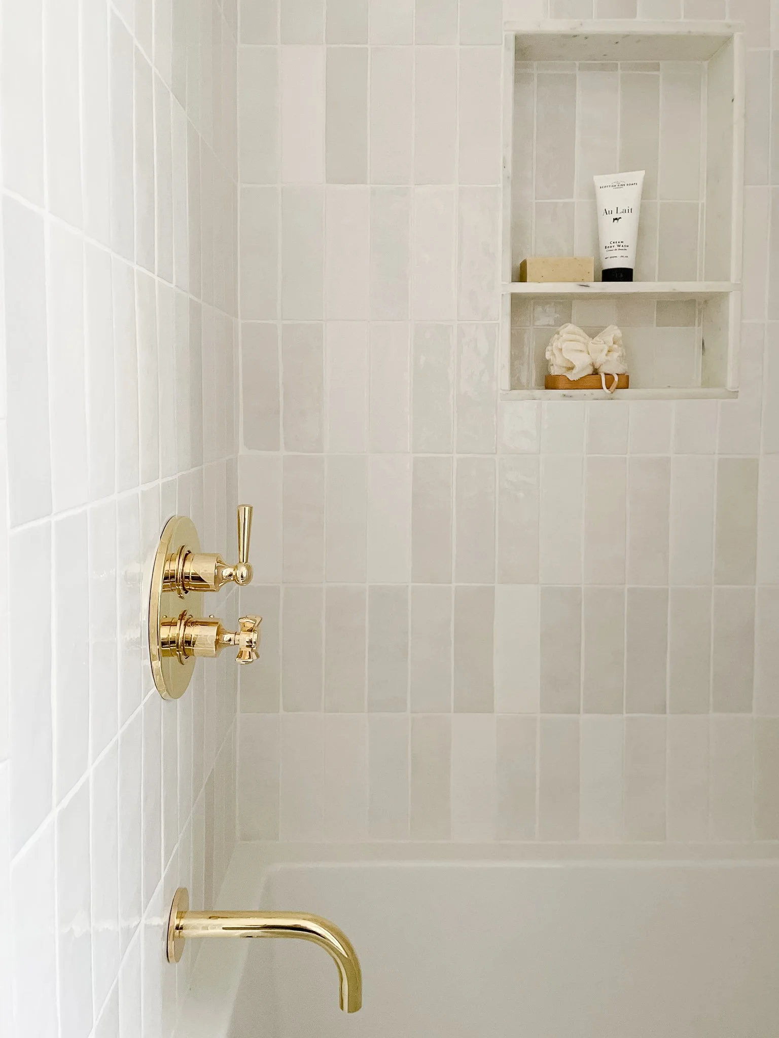 High-end home renovation in Central Lonsdale by Quay Construction featuring a modern bathroom with white textured tiles and brushed gold fixtures.