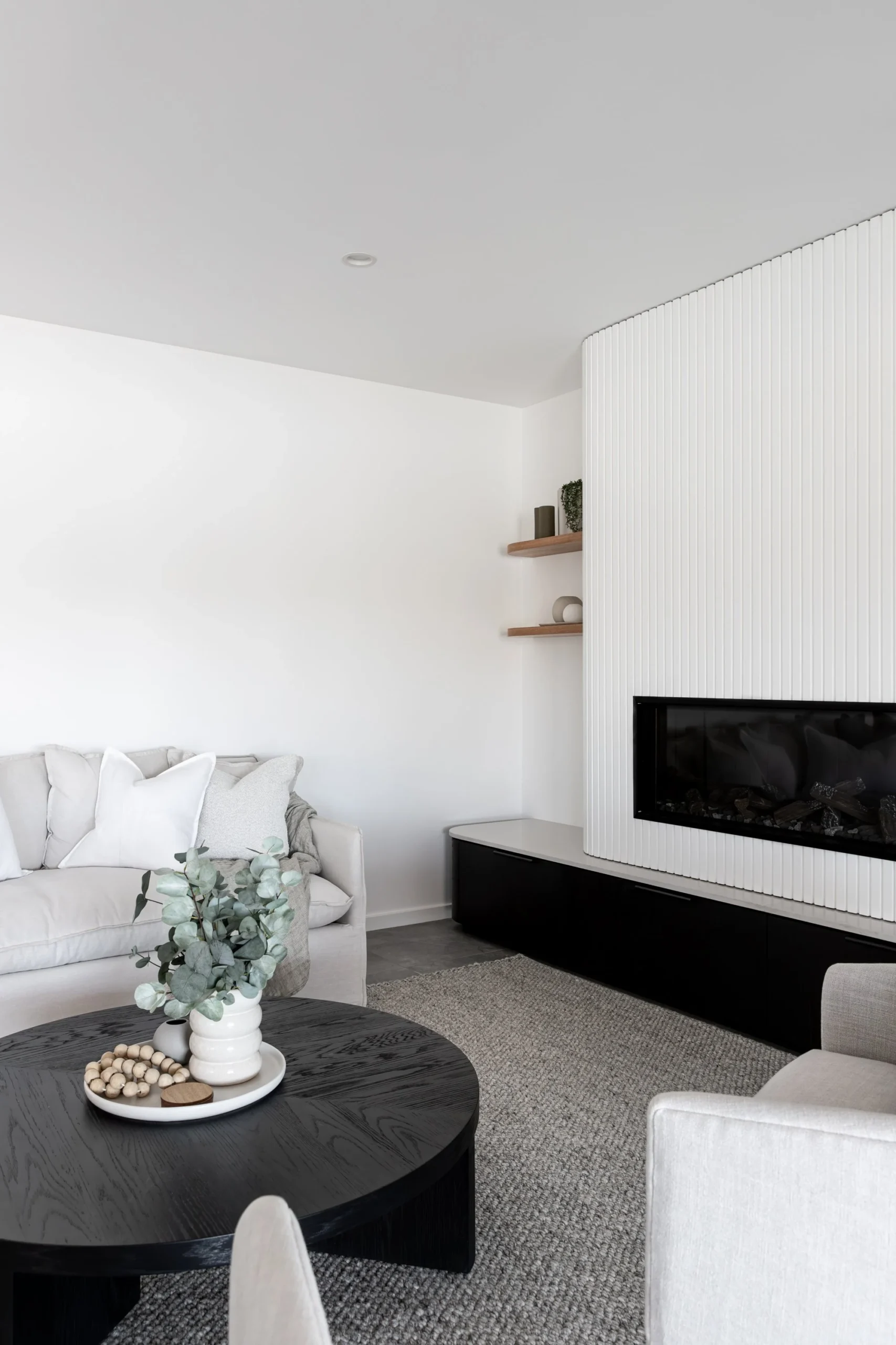 Finished basement living and dining area by Quay Construction in Vancouver, featuring modern grey flooring, recessed lighting, and a white dining set.