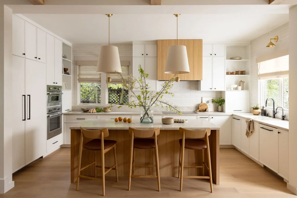 Modern kitchen renovation in Ambleside by QUAY Construction featuring white cabinetry and wood island