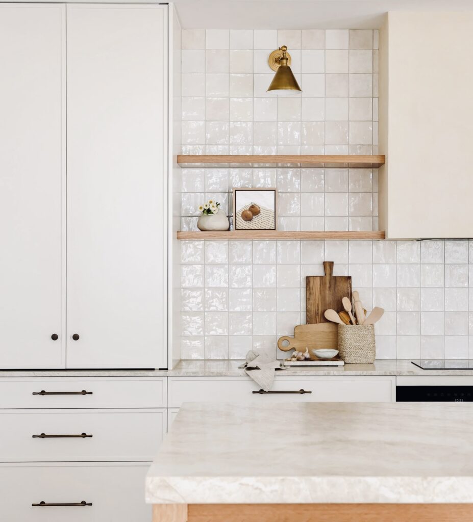 Luxury home renovation in Kitsilano by Quay Construction featuring a modern kitchen with a large waterfall island, minimalist white cabinetry, and gold pendant lighting.