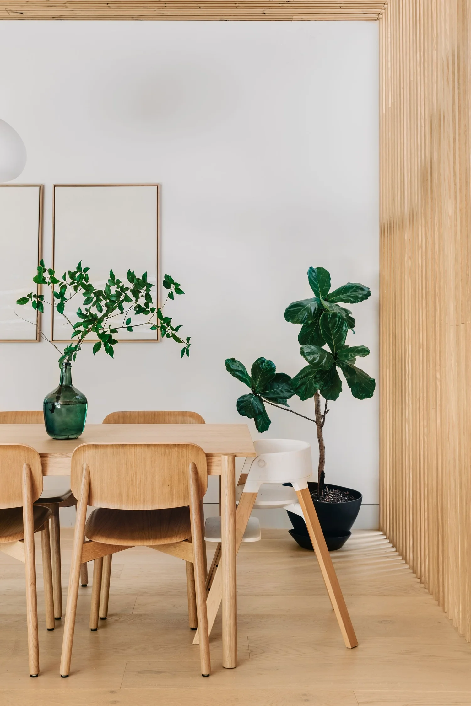 Modern dining area with oak furniture and a slatted wood accent wall from a professional home renovation in West Cambie by Quay Construction