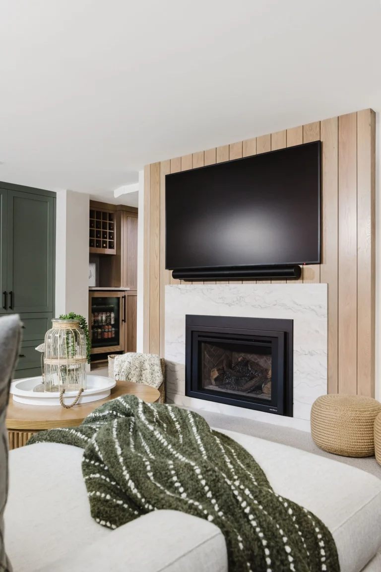 Modern basement renovation in Burnaby featuring custom fireplace media wall, wood paneling, and built-in cabinetry by licensed basement renovation contractor