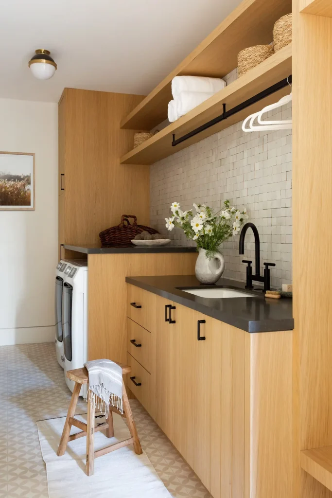 Modern laundry room renovation in Deep Cove featuring custom white cabinetry and integrated appliances by QUAY Construction