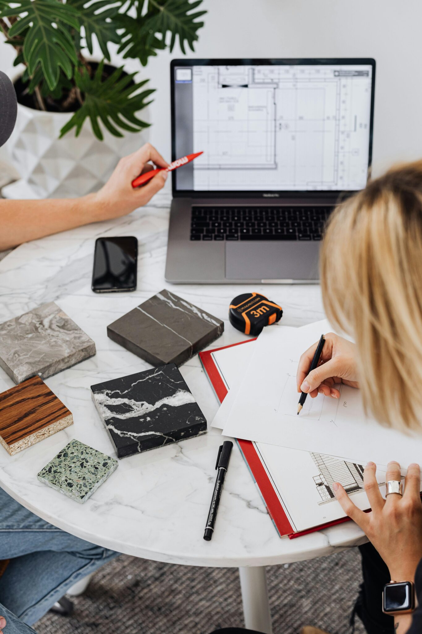 Designers reviewing marble samples and digital floor plans for a kitchen renovation Vancouver by QUAY Construction.