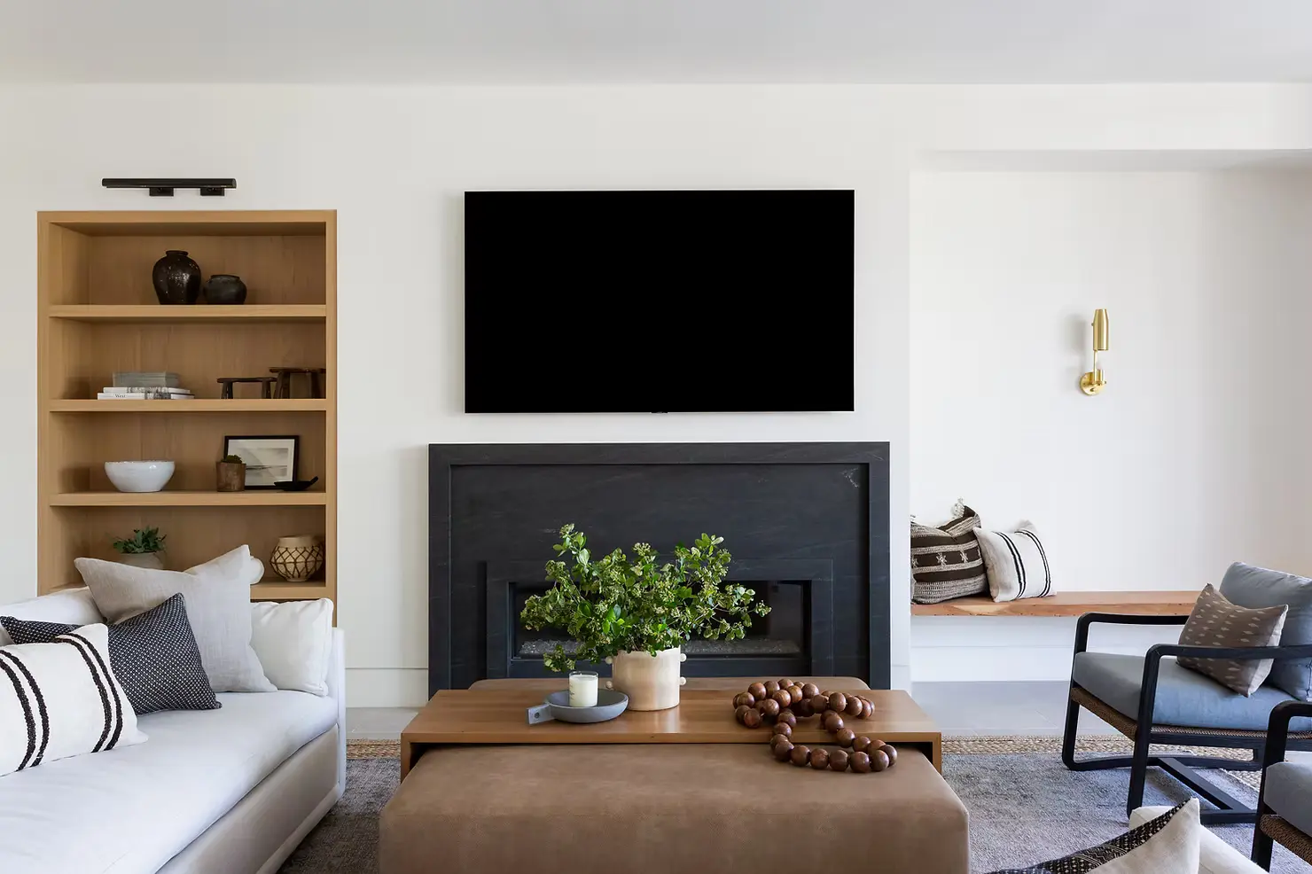 Modern living room home renovation in Surrey featuring a custom black fireplace, built-in oak shelving, and contemporary furniture by QUAY Construction.