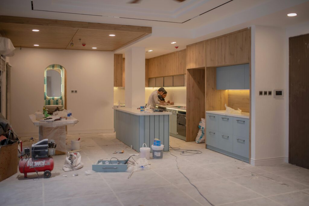 Active construction site of a kitchen renovation Vancouver with teal cabinetry and wood accents being installed.