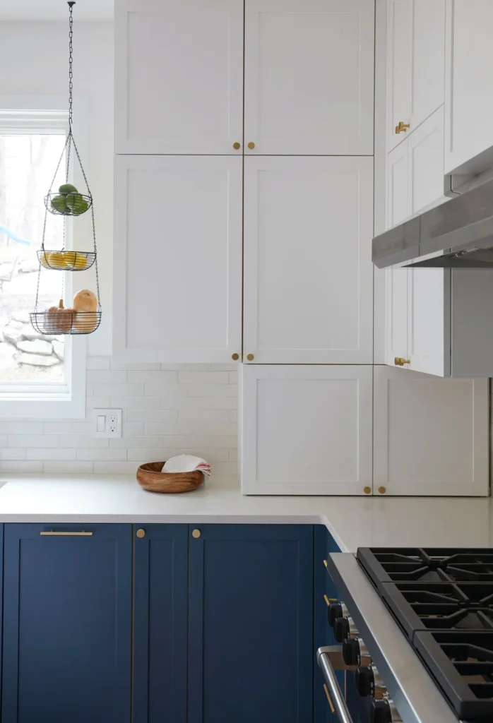 Modern kitchen renovation in Vancouver featuring navy blue lower cabinets, white upper shaker cabinets, and gold hardware.