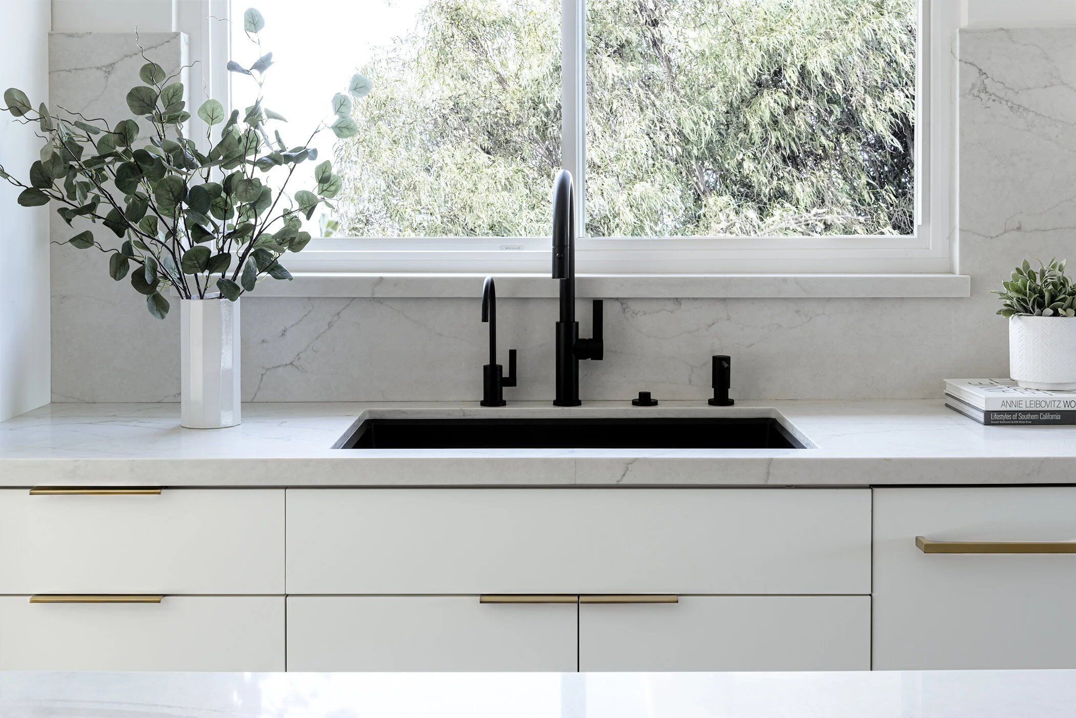 Modern kitchen renovation Vancouver featuring a matte black faucet, white cabinetry, and marble backsplash.