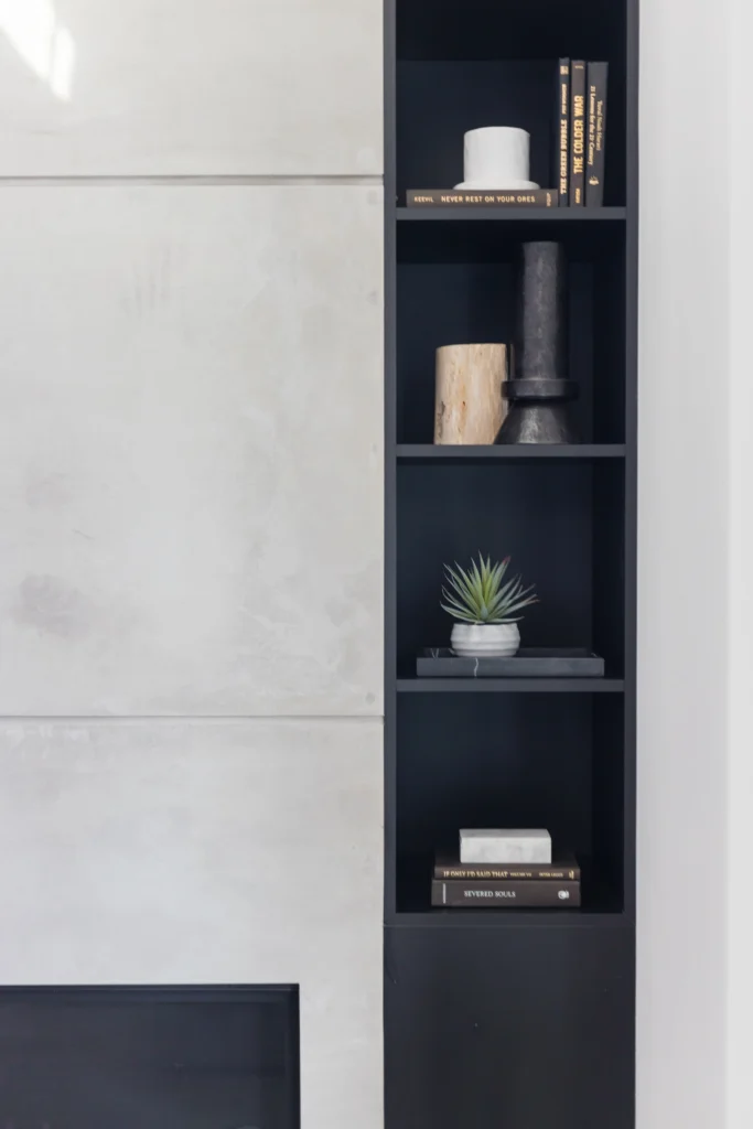 Home renovation Central Lonsdale featuring a concrete-finish fireplace and minimalist black built-in shelving.