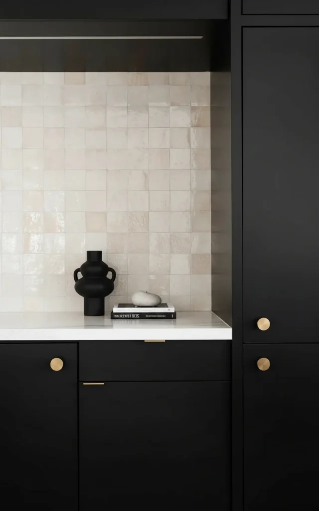 Modern Vancouver kitchen featuring matte black cabinetry, gold hardware, and zellige tile backsplash for a luxury renovation.