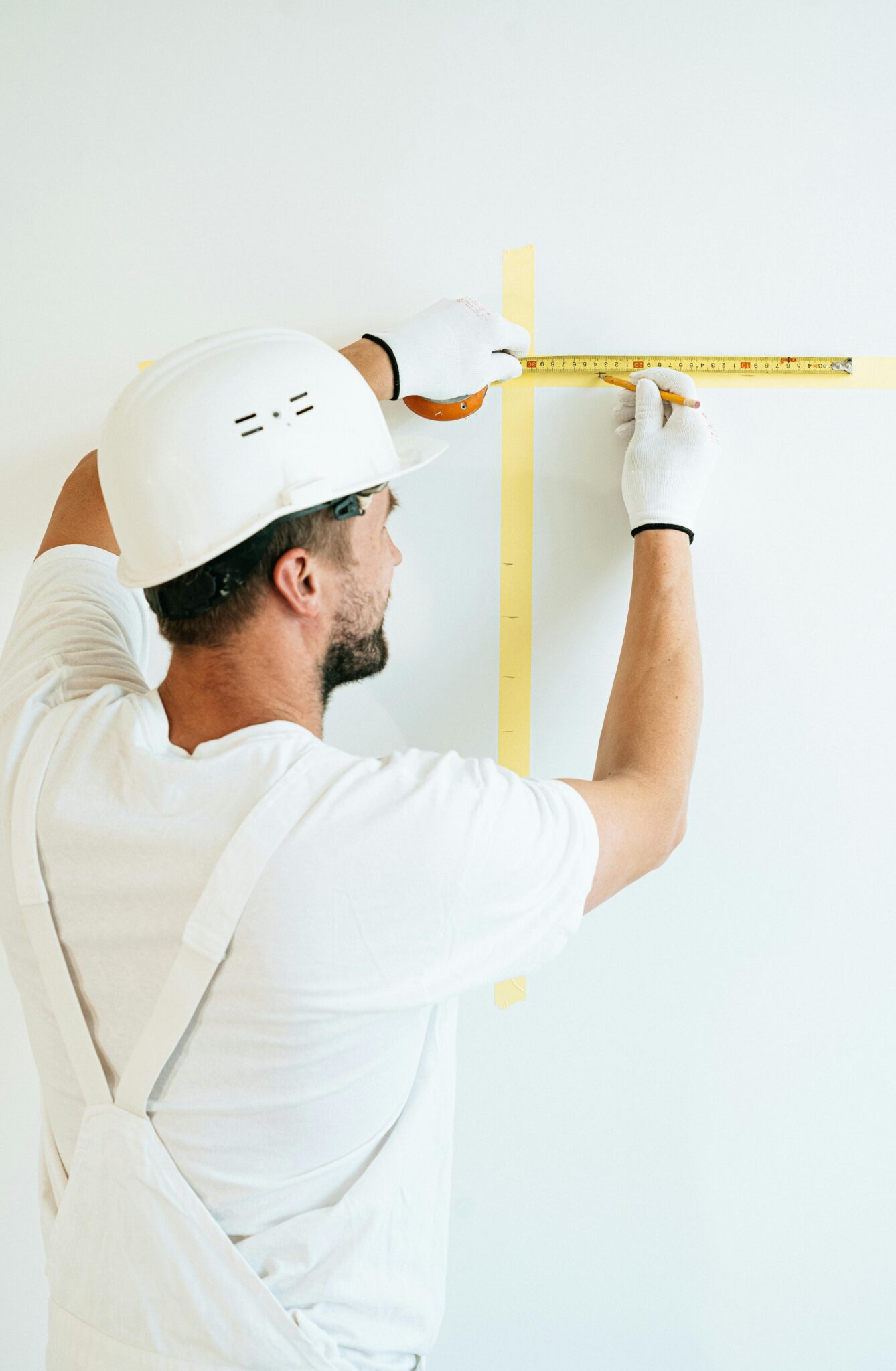Contractor measuring a wall to prepare for applying Benjamin Moore bathroom paint colors during a home renovation.