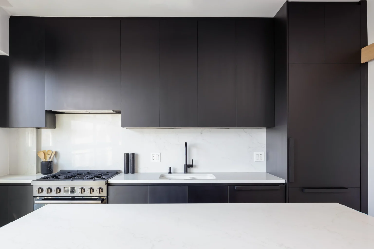 Modern kitchen renovation in a West Vancouver condo with black cabinets and quartz countertops