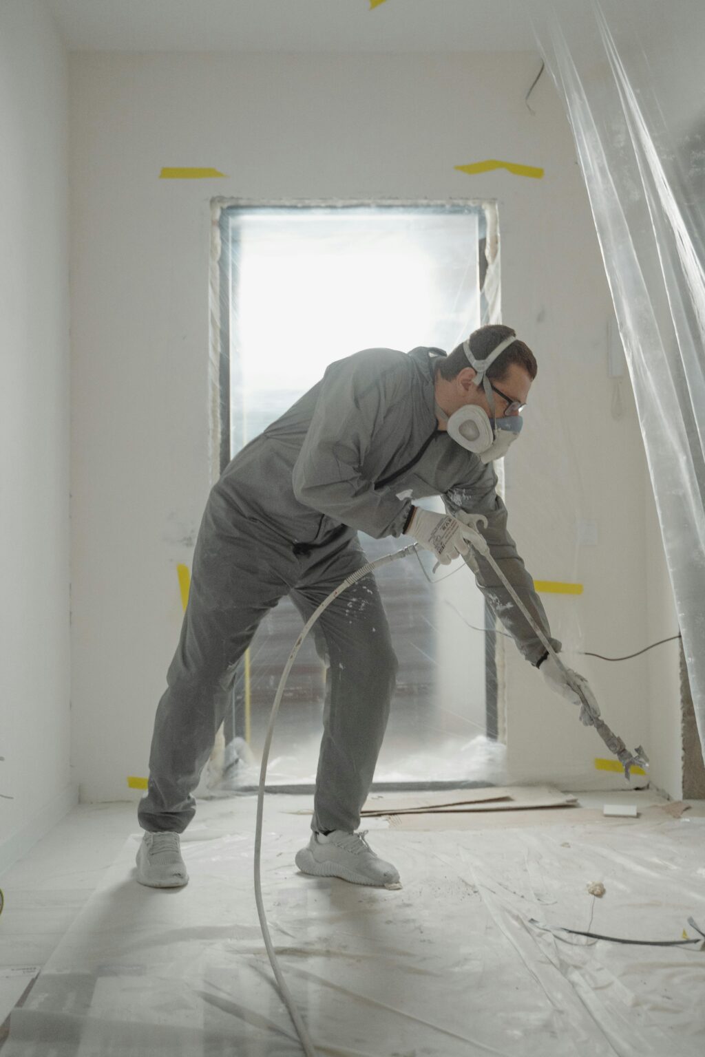 Professional painter using a spray gun to apply Benjamin Moore kitchen paint colors during a luxury home renovation.