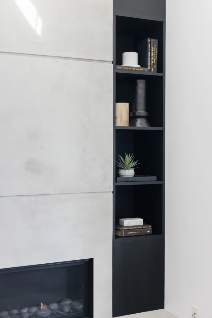 Modern concrete fireplace surround with black minimalist built-in shelving for City Centre Richmond home renovations.