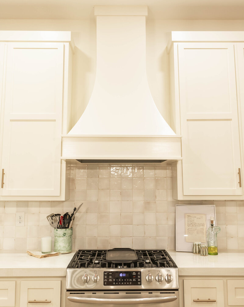 Custom white range hood and tile backsplash for a luxury kitchen renovation Vancouver project by QUAY Construction.