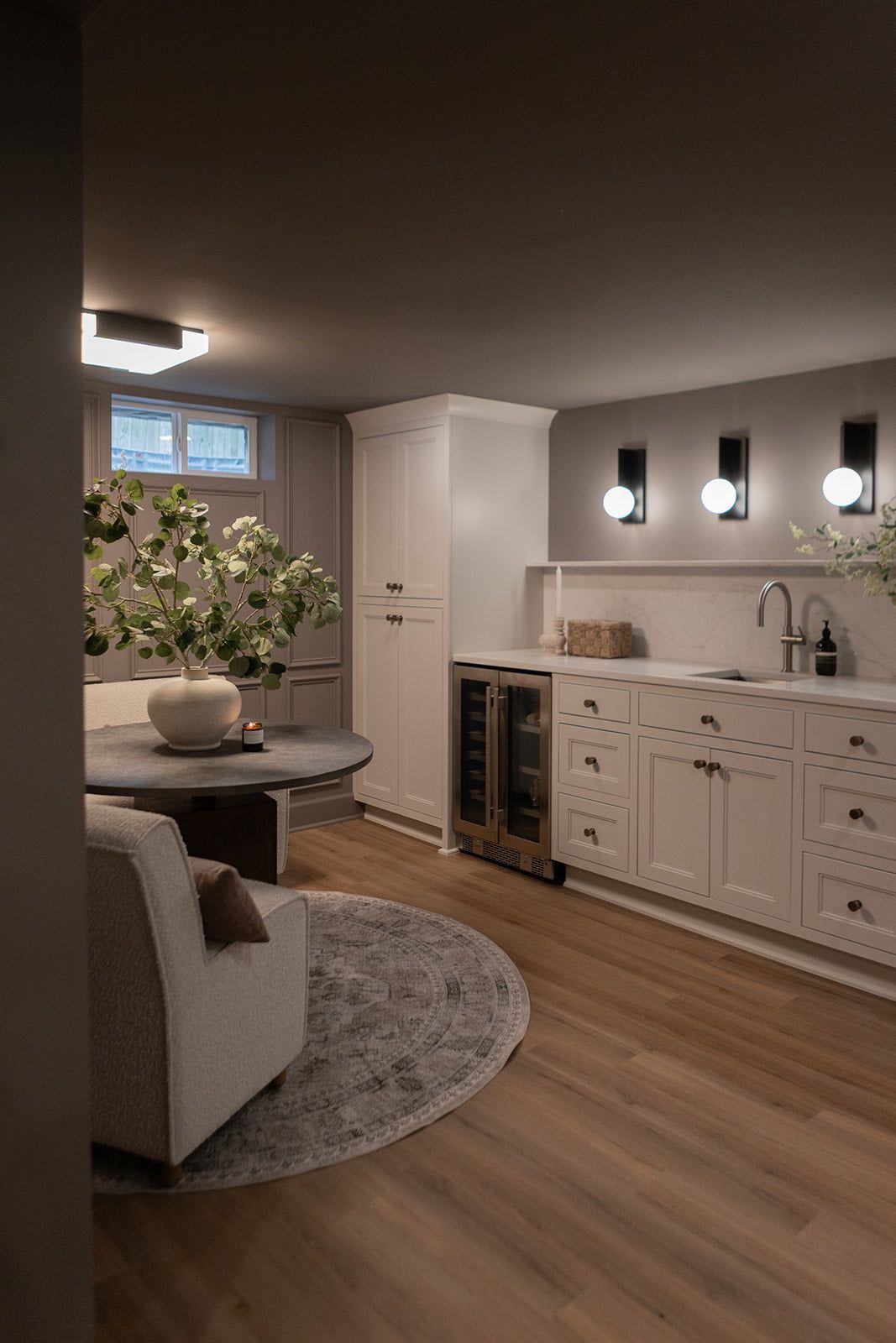 Modern secondary suite kitchenette in Vancouver with white cabinetry, wine fridge, and integrated dining.