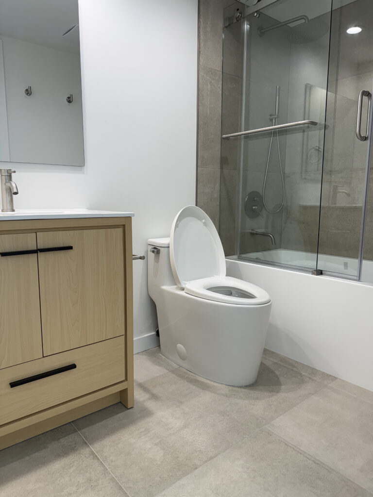 Modern Yaletown condo bathroom renovation with frameless glass shower, custom vanity, and large-format tile by QUAY Construction