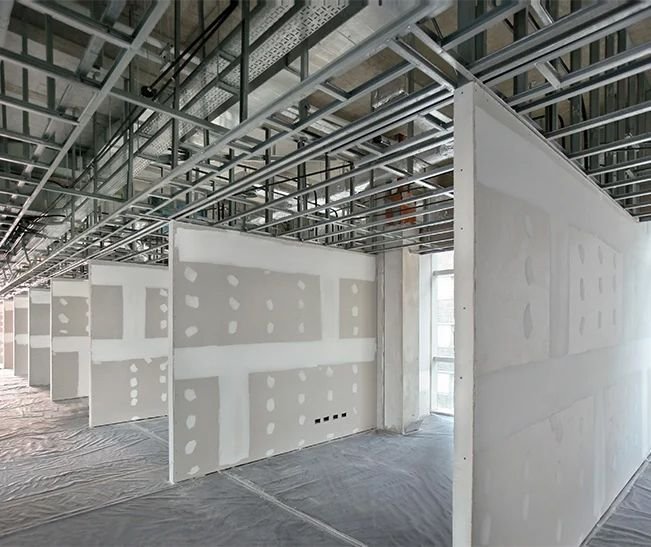 Office interior under construction with framing, drywall and exposed ceiling services