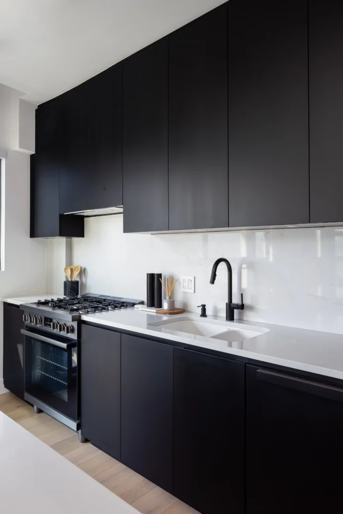Modern kitchen renovation in Vancouver featuring custom black cabinets, quartz countertops, integrated backsplash, and premium appliances by QUAY Construction.