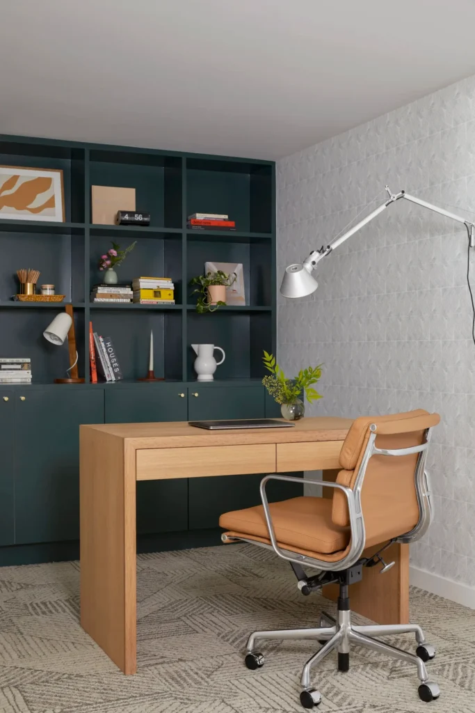 Home office in a finished basement renovated by Quay Construction featuring custom dark green built-in shelving and a modern oak desk.