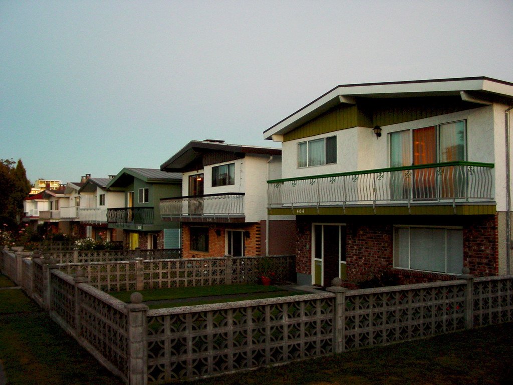 A row of Vancouver Special houses with brick ground floors, stucco upper floors and full-width balconies