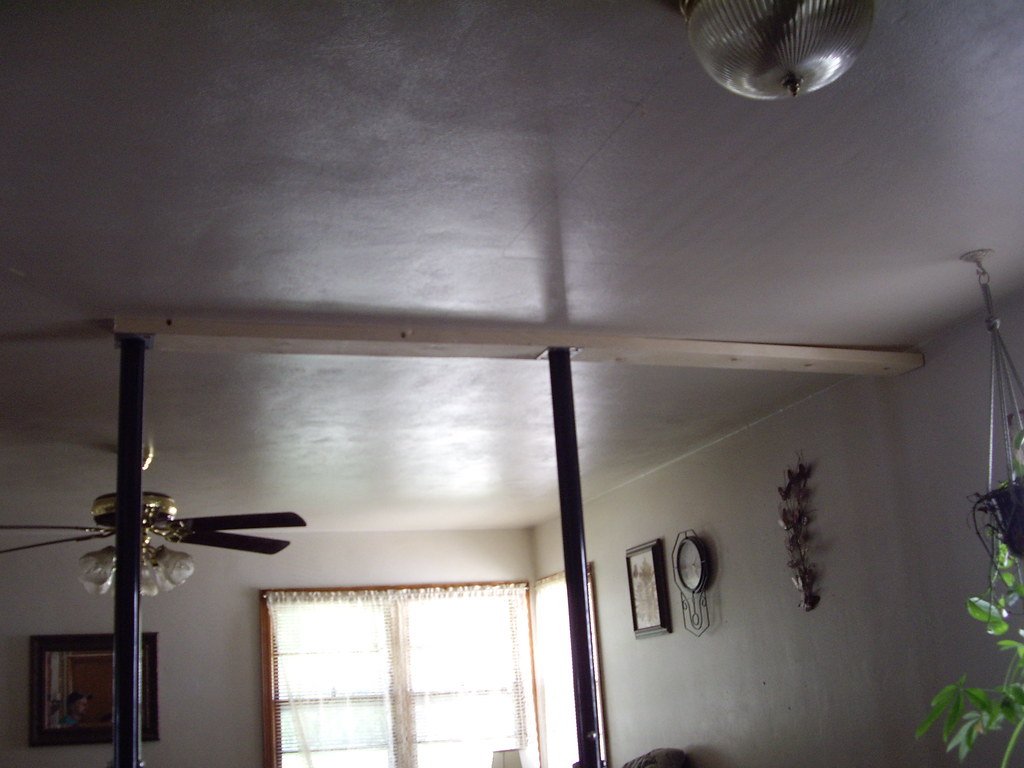 A room with a new ceiling beam held up by posts where an interior wall was removed