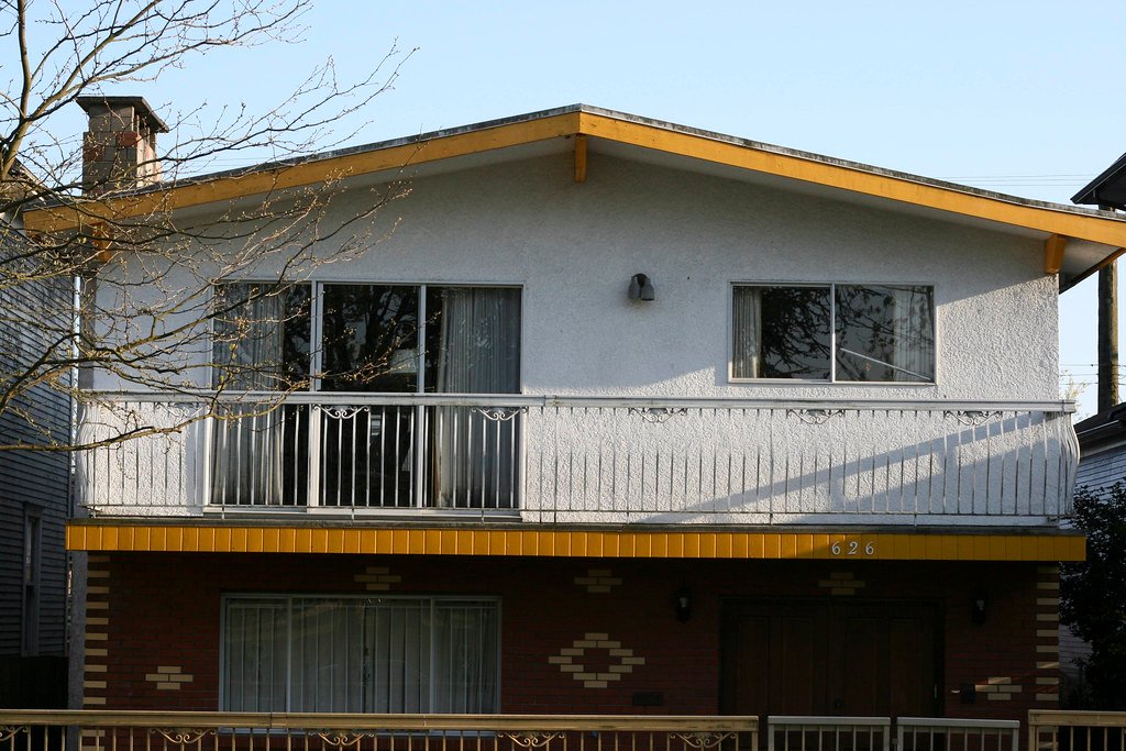 A classic Vancouver Special with a low-pitched roof, upstairs balcony and brick ground floor