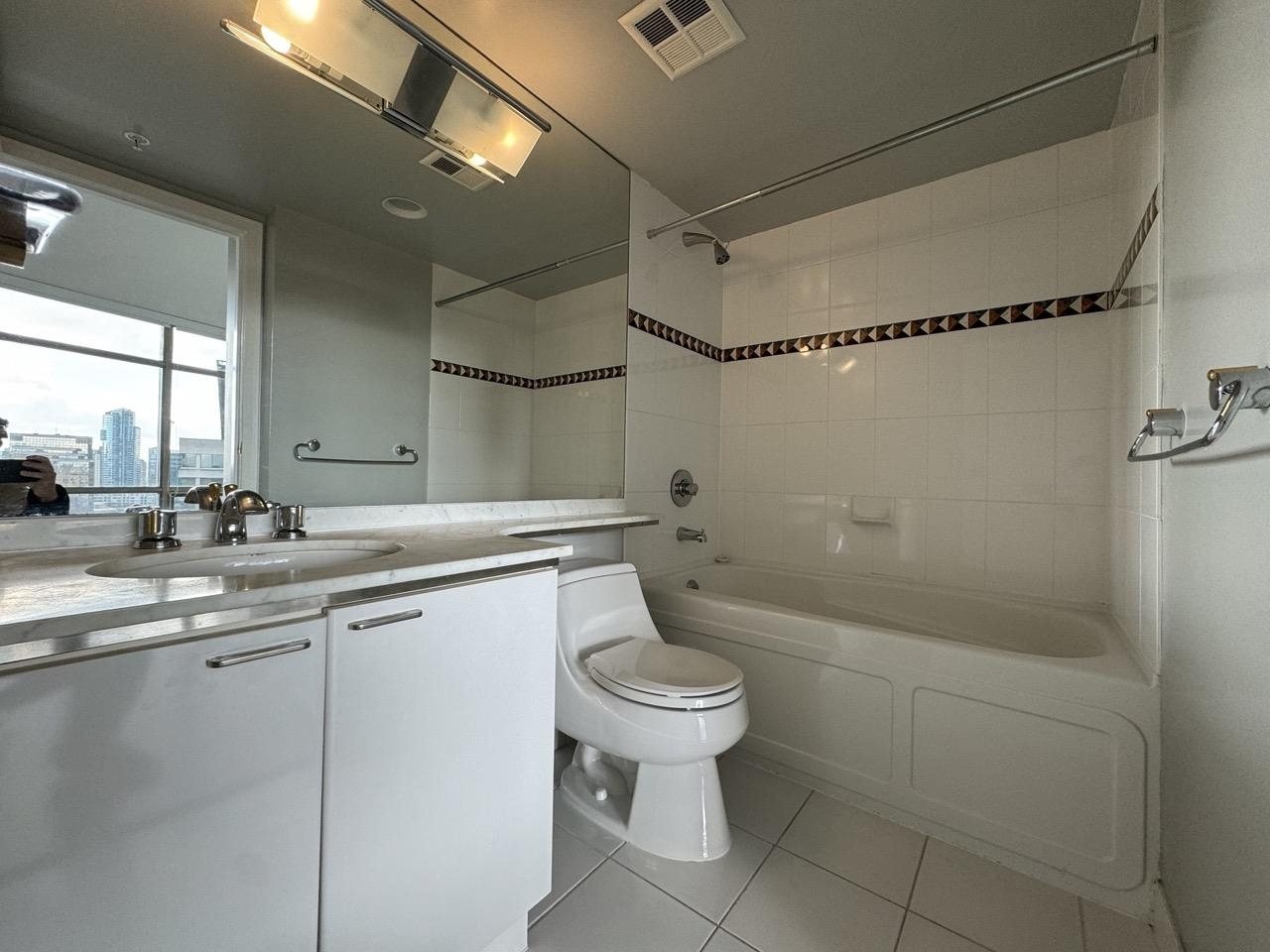Before: condo ensuite with a tub and tiled surround in downtown Vancouver