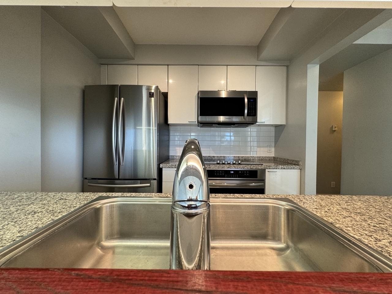 Before: condo kitchen with granite counters and a double sink at the breakfast bar in downtown Vancouver