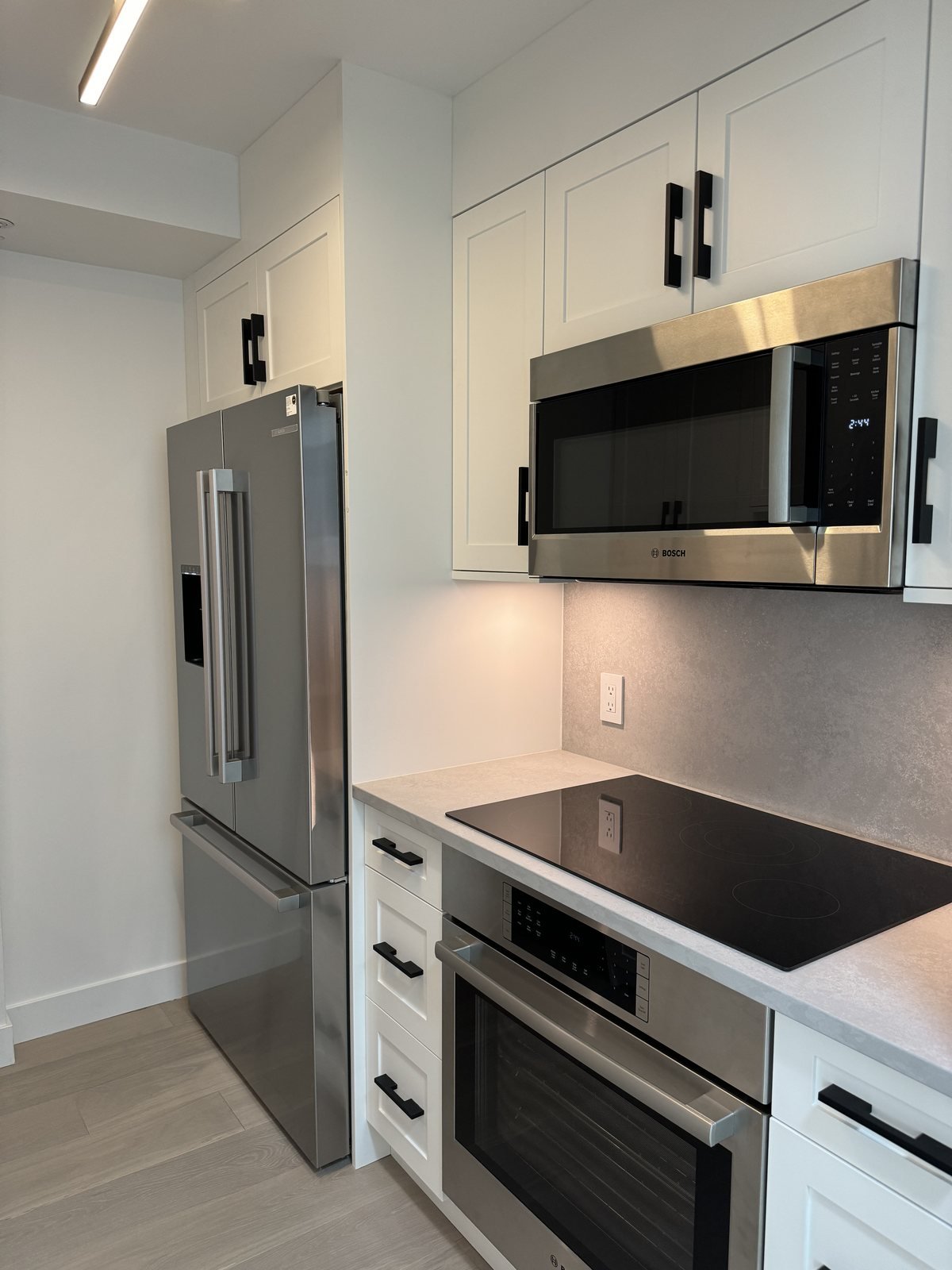 Cooktop, wall oven and over-the-range microwave in a renovated downtown Vancouver condo kitchen