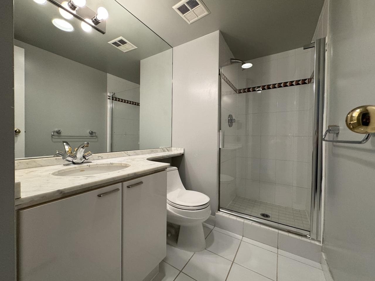 Before: condo main bathroom with a stall shower and long vanity in downtown Vancouver