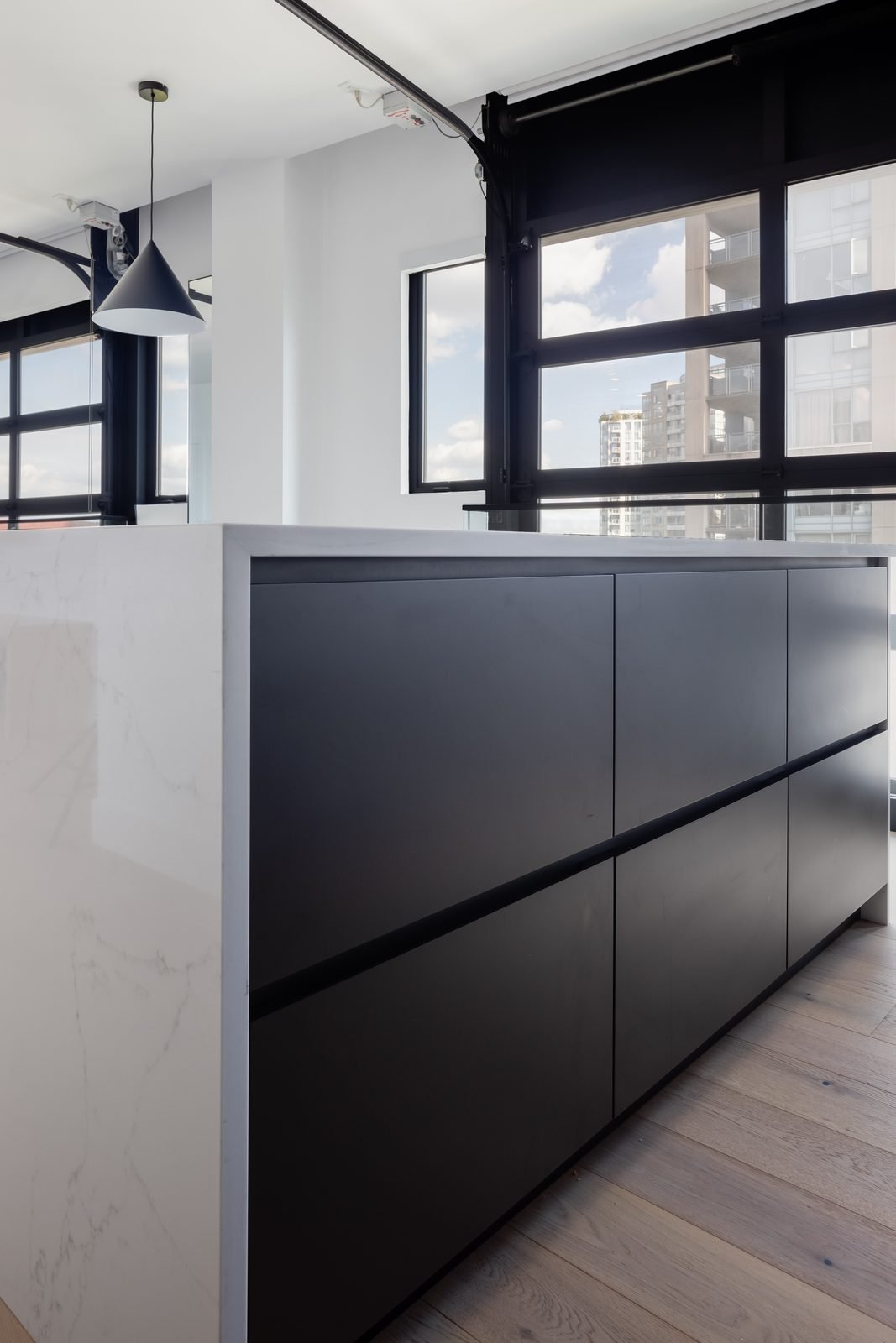 Matte black island storage with a quartz waterfall edge in a Downtown Vancouver kitchen renovation