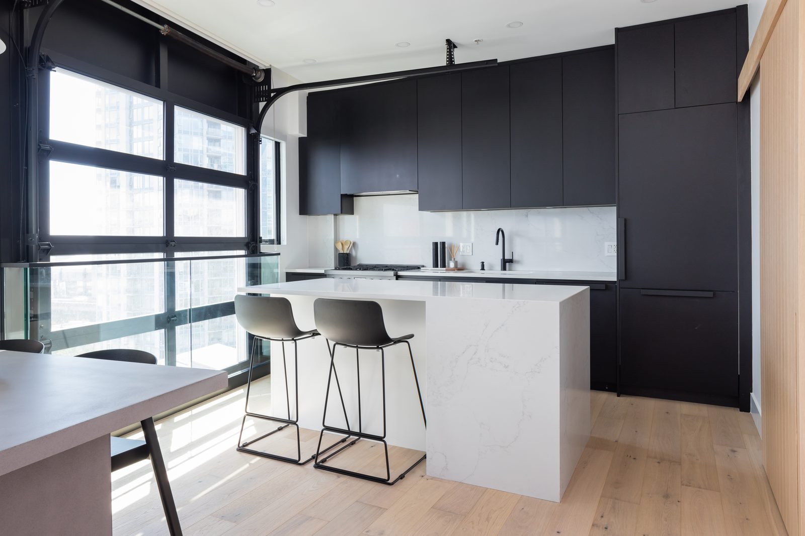 Open kitchen and dining area with a quartz waterfall island in a Downtown Vancouver loft condo